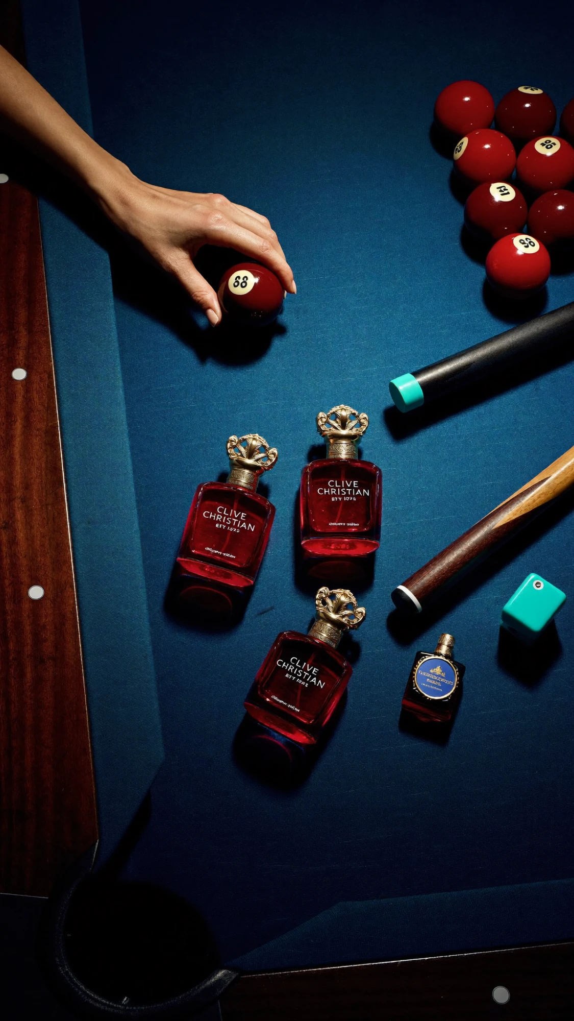 Concept for Clive Christian: red perfume bottles with gold crown caps laid on a blue billiard table